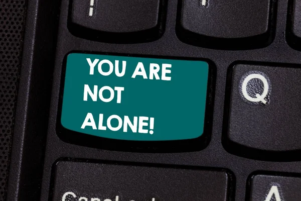 Text sign showing You Are Not Alone. Conceptual photo Offering help support assistance collaboration company Keyboard key Intention to create computer message pressing keypad idea.