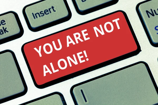 Text sign showing You Are Not Alone. Conceptual photo Offering help support assistance collaboration company Keyboard key Intention to create computer message pressing keypad idea.