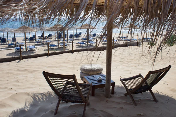 Paraguas de techo de paja Proyección de la luz del sol. Muebles frente al mar frente al océano azul. Cerca de la barrera de división de área para los bañistas. Ideas de vacaciones de viaje . — Foto de Stock