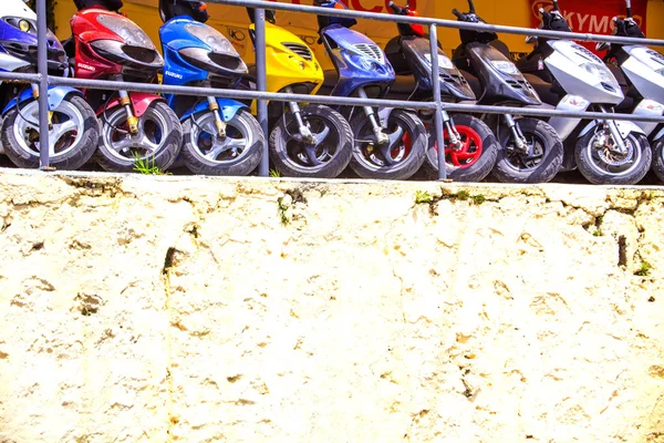 Collectie van kleurrijke motorfietsen geparkeerd. Scooters voering voor Display. Minibikes voor weergave buiten een hoge Storefront. Winkel verkopen tweefasen Wheeler. — Stockfoto