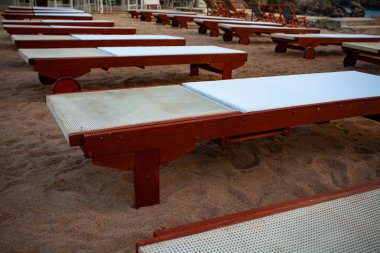 Üst üste dizilmiş beyaz yastık ile ayarlanabilir ahşap RECLINER. İyi bir Sandy sahilde konuşlu tekerleği ile boş açık düz şezlong. Seyahat tatil fikirleri