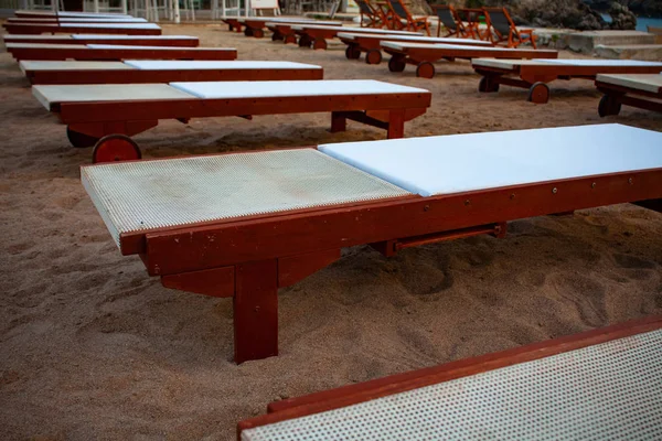 Üst üste dizilmiş beyaz yastık ile ayarlanabilir ahşap RECLINER. İyi bir Sandy sahilde konuşlu tekerleği ile boş açık düz şezlong. Seyahat tatil fikirleri