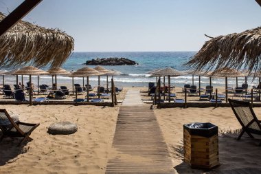 Okyanusta kaya oluşumu. Dokuma şemsiye, ayarlanabilir katlanmış ve gelişeceğini plaj sandalye yatak denize karşı karşıya. Ahşap ince kum mavi su ki yolda.