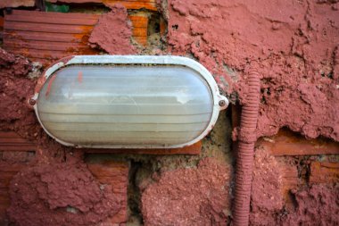 Bitmemiş duvara monte fikstür aydınlatma uzamış. Esnek elektrikli tel koruyucu tüp düzgün yüklenmemiş. Dağınık Aplik yükleme closeup.