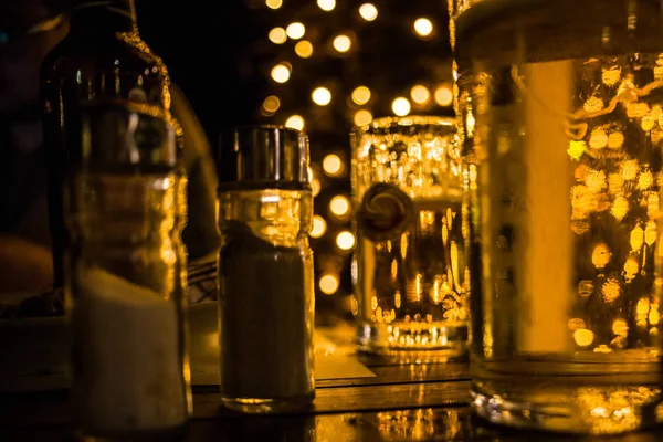 Closeup Shot of Table com Sal e Pepper Shaker. Óculos Cheio de Espumante Líquido de Luzes no Fundo. Foto no efeito Bokeh imagem embaçada . — Fotografia de Stock