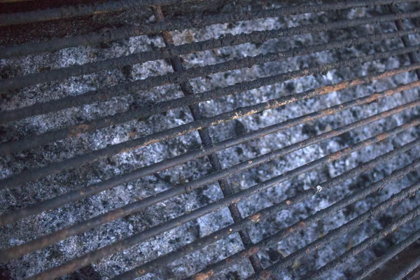 Kochen im Freien durch Grillen. leere, verkohlte Grillrost, der gereinigt werden muss. Rost und Verbrennungen kleben am Stahlgitter. Asche und Holzkohlereste in Grubenblech. — Stockfoto
