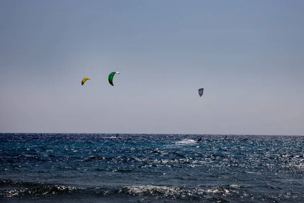 Wave Riders on Board Flying Power Kites on the Wavy Crystal Blue Ocean. Морской спорт по назначению. Кайтсерфингисты наслаждаются водными видами спорта в праздничный день . — стоковое фото