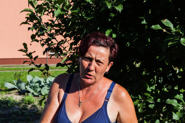 Сосредоточенный взгляд на женщину, горячо смотрящую в один солнечный день. Брюнетка домохозяйка в лифчике за деревом. Летний стиль одежды. Типичная одежда для жаркого дня
.