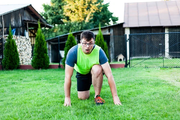 Ein Mann mit Brille und erstauntem Gesichtsausdruck, während er sich auf die tägliche Bewegung im Rasen vorbereitet. gesunde Lebensweise. Wellness- und Fitness-Ideen. — Stockfoto