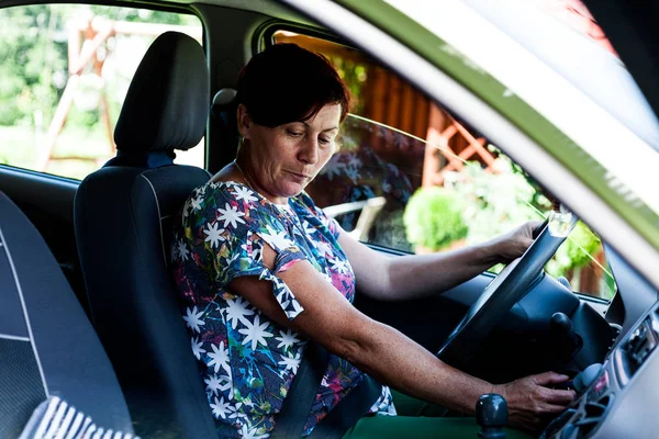Sebevědomá žena drží volant moderního automobilu. Řidič dáma při pohledu dolů řadicí páky převodovky připravuje na přechod. Moderní životní styl a pohodlí. Cestování a volný čas. — Stock fotografie