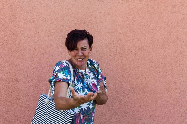 Eine fröhliche Amerikanerin, die mit Handbewegungen breit lächelt. Der Rentner bereitet sich auf einen kurzen Besuch im Einkaufszentrum vor. Den freien Tag genießen. Ideen zur Entspannung und Entspannung. — Stockfoto