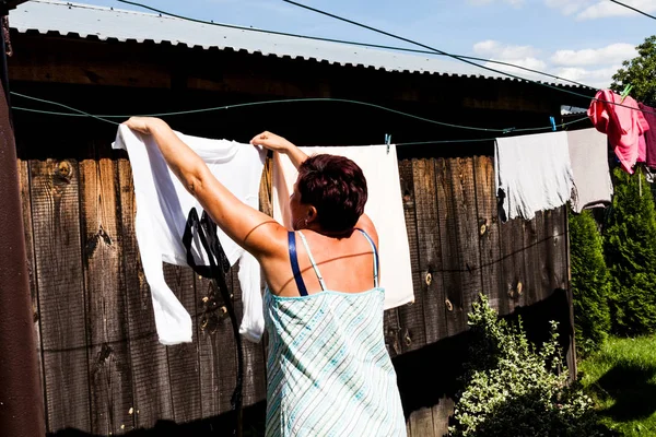 Arkadan görünüşü giyim güneş kuru için evin dışında asılı iken tipik ev elbise giyen bir kadın. Dize ve küçük yere düşmesini giysiler güvenli hale getirme. Kentsel yaşam.