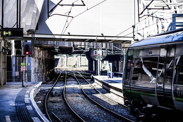 Birmingham, uk - märz 2018 zug auf bahngleis unter einer struktur. U-Bahn-Bordstein am anderen Ende. Teil eines Busses mit glänzenden Glasfenstern. Kabeldrähte hängen oben. — Stockfoto