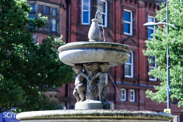 Birmingham, Verenigd Koninkrijk - maart 2018 fontein gemaakt van steen in St. Peters tuin in Wolverhampton, Engeland. Ontworpen met ondersteuning van de cijfers van de kinderen een grote ronde kom op hun hoofd met Water. — Stockfoto