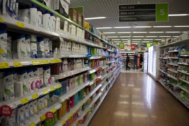 Birmingham, İngiltere - Mart 2018 Asda iç koridor tuvalet süpermarkette. İnsanlar kişisel öğeler için alışveriş. Bölüm tabela yukarıda asılı. Kırmızı Satılık Etiketler seçilen mal.