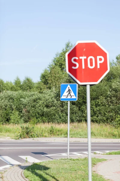 Street traffic with STOP sign on a sunny day. Stop sign for traffic against blue sky and green forest.