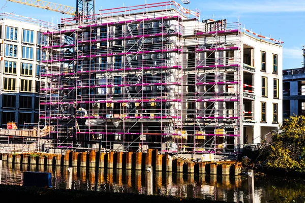 Bouwplaats waarop grote gebouwen met beschermende metalen structuren zijn gebouwd. Nieuwe gebouwen op de bouwplaats. Bouwplaats aan de kant van de rivier. — Stockfoto