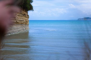 Sakin mavi deniz ve mavi gökyüzü ile güzel bir manzara. Kayalık tepenin denizin kenarında. Doğa ve deniz ile tatil kavramı.