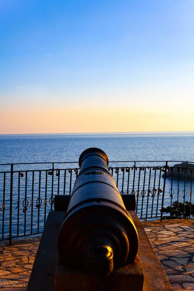 Vieux canon de château en métal sur le mur. Canon antique en fer sur le bord de mer. Ciel bleu au-dessus de la mer . — Photo