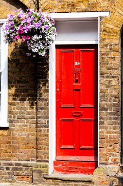 Eski kırmızı tuğla ev kırmızı ahşap kapılarda. Evin duvarına çiçekler.