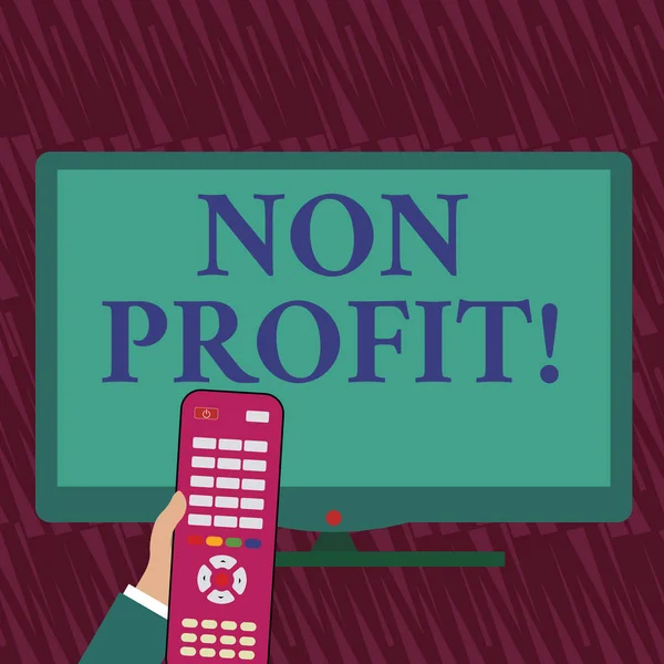 Text sign showing Non Profit. Conceptual photo not making or conducted primarily to make profit organization Hand Holding Computer Remote Control infront of Blank Wide Color PC Screen.