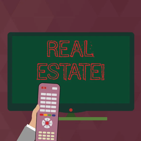 Writing note showing Real Estate. Business photo showcasing owning property consisting of empty land or buildings Hand Holding Remote Control infront of Wide Color PC Screen.