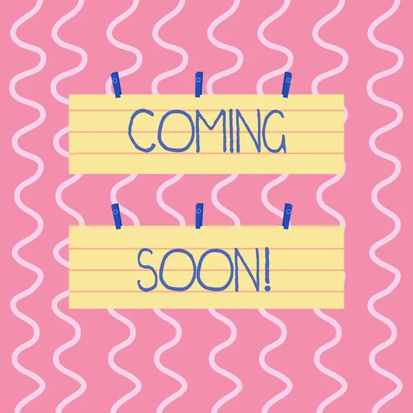Text sign showing Coming Soon. Conceptual photo event or action that will happen after really short time Two Color Blank Strip Size Lined Paper Sheet Hanging Using Blue Clothespin.
