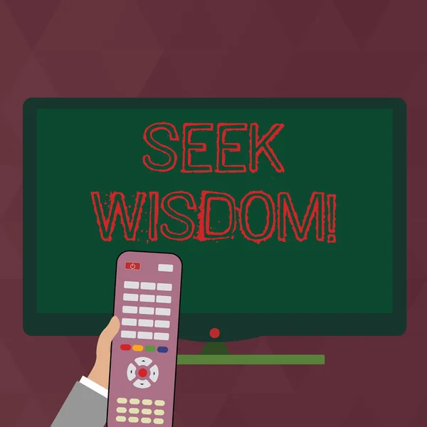 Writing note showing Seek Wisdom. Business photo showcasing ability to think act using knowledge experience understanding Hand Holding Remote Control infront of Wide Color PC Screen.