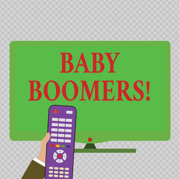 Escritura a mano conceptual que muestra Baby Boomers. Texto de la foto de negocios que demuestra quién nace en años después de la Segunda Guerra Mundial de la mano que sostiene el control remoto frente a la pantalla amplia de PC a color . — Foto de Stock