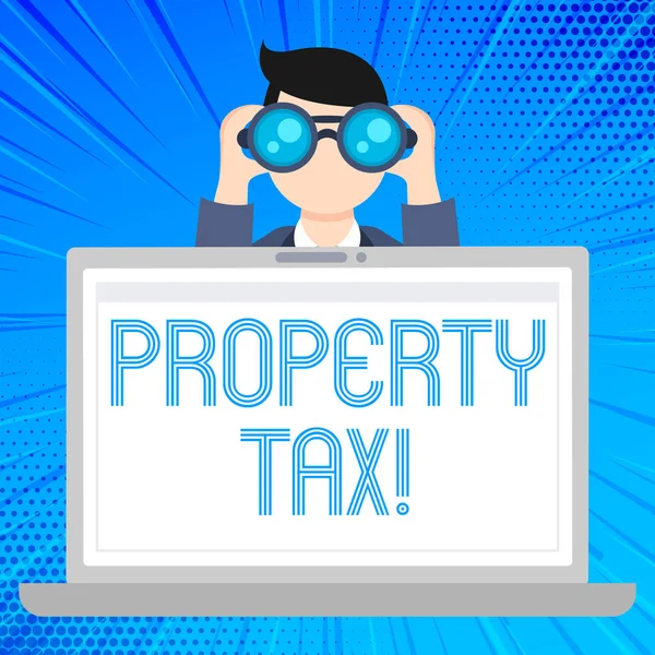 Writing note showing Property Tax. Business photo showcasing bills levied directly on your property by government Man Holding and Looking into Binocular Behind Laptop Screen.