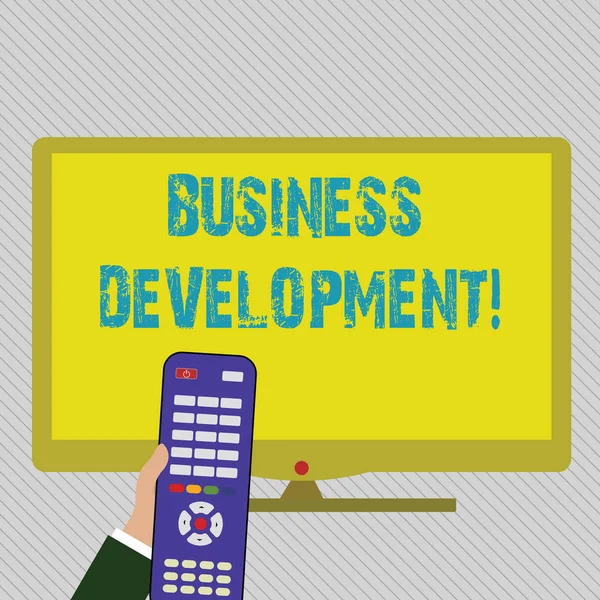Text sign showing Business Development. Conceptual photo pursuing strategic opportunities for a certain business Hand Holding Computer Remote Control infront of Blank Wide Color PC Screen. — Stock Photo, Image