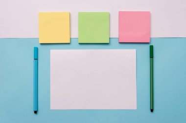 Renkli zemin in üstündeki kağıtları ve kalemi not edin. Yumuşak tonit yüzeyinin üstüne yerleştirilen pastel renk sabit. Düz düzenleme sanatsal yolu fotoğraf bırakır