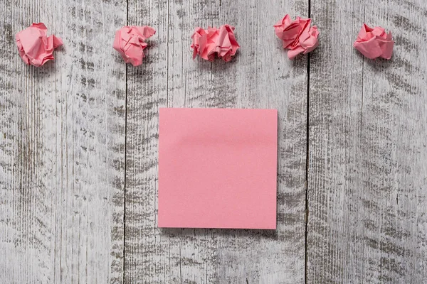 Serie spessa di carta semplice nota con scarti sul tavolo con texture in legno. Lenzuola bianche rosa e rifiuti sopra tavoletta di legno modellato. Idea creativa sull'organizzazione dello spazio di lavoro — Foto Stock
