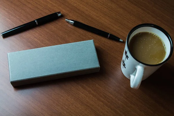 Zwei Kugelschreiber mit Etui-Set Kaffeetasse liegen auf einem Holztisch. hervorragend für die Vorbereitung auf Essay für Arbeit, Job, Projekt, Hausaufgaben schreiben — Stockfoto