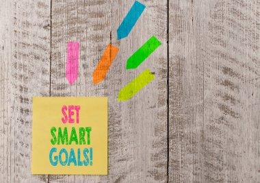Set Smart Goals'ı gösteren kavramsal el yazısı. Fikirlerinizi netleştirmek için iş fotoğrafı metin listesi odak çabaları akıllıca ahşap masa masasının üstüne kağıt ve çizgi ok çıkartmaları not kullanın.