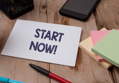 Kelime yazma metni Şimdi Başla. İş konsepti: Çalışmaya başla ya da hemen bir şeyler yap Üst görünüm tahta masa sabit kağıt tablet kalem kalem renkli çubuk bloknot.