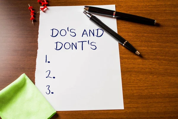 Text sign showing Do S And Dont S. Conceptual photo Rules or customs concerning some activity or actions Blank stationary paper wooden table fountain pen cloth rag pins to fix. — Stock Photo, Image