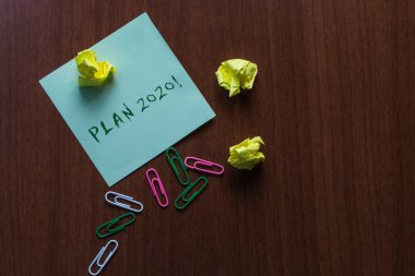 Word writing text Plan 2020. Business concept for detailed proposal for doing or achieving something next year Upper view three small paper balls colored clips stick pad wooden table. clipart