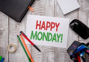 Mutlu Pazartesi 'yi gösteren bir not yazıyorum. İş fotoğraflarının sergilenmesi, bu gösteri sırasına göre ona harika bir yeni hafta dileklerini iletiyor. Kırtasiye ve bilgisayar malzemeleri. Masasında kağıt kağıtlar olan kalem..