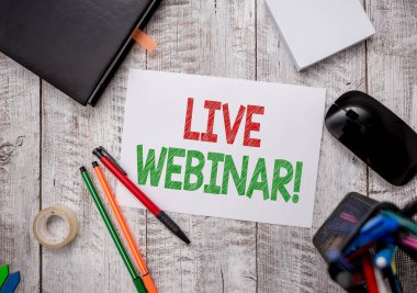 Canlı Webinar 'ı gösteren bir not yazıyorum. İş fotoğrafı tanıtım konferansı ya da seminer masanın üzerinde kağıt kağıtlarla birlikte Web Sabit ve bilgisayar malzemesi kaleminden iletiliyor.