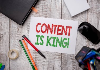 İçeriğin Kral olduğunu gösteren bir not yazıyorum. İş fotoğraflarının sergilenmesi pazarlama odaklı görünürlük, ödenmemiş arama sonuçları sabit ve bilgisayar zımbırtıları masa üzerinde kağıt kağıtlarla kalem..