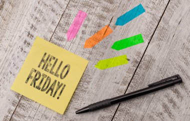 Hello Friday 'i gösteren bir not yazıyorum. İş fotoğraflarının sergilenmesi, yeni haftanın başından itibaren mutluluğu ifade etmek için kullanılır. Tahta masanın tepesindeki kağıt ve çizgi ok çıkartmaları..