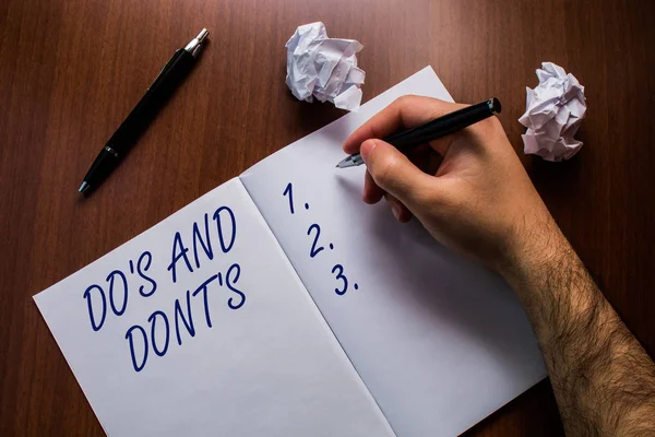 Señal de texto que muestra Do S Y Dont S. Conceptual foto Reglas o costumbres relativas a alguna actividad o acciones Superior vista de cerca portátil abierto mano bolígrafo bolitas de papel mesa de madera . — Foto de Stock