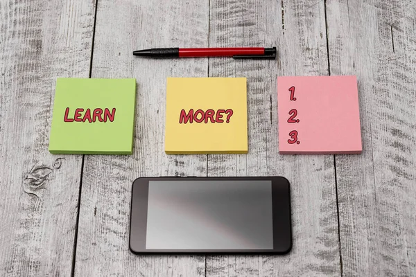 Writing note showing Learn More question. Business photo showcasing gain knowledge or skill studying practicing Stationary equipment and phone with paper sheets on the wooden desk. — 스톡 사진