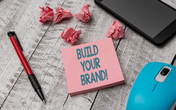 Text sign showing Build Your Brand. Conceptual photo creates or improves customers knowledge and opinions of product Writing equipment and paper plus scraps with gadgets on the wooden desk. — 스톡 사진