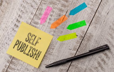 Self Publish 'i gösteren bir not yazıyorum. Ticari fotoğraf sergisi yazarı bunlardan birini yayınlar bağımsız olarak çalışır Not kağıdı ve çizgi ok etiketleri ahşap masa üzerinde.