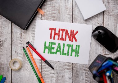 Think Health 'i gösteren bir not yazıyorum. Tam fiziksel ve sosyal refahın tam fiziksel ve sosyal durumunun yer aldığı iş fotoğrafı gösterimi masasında kağıt kağıtlar olan kalem ve bilgisayar malzemeleri.