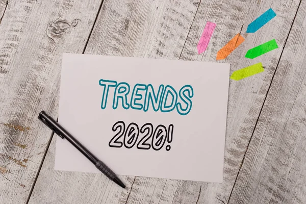 El yazısı metin Trends 2020. Bir şeyin ahşap masanın üzerinde kalem olan Düz not kağıdı ve çizgi ok çıkartmaları geliştirdiği veya değiştirdiği genel yön anlamına gelen kavram. — Stok fotoğraf