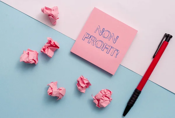 Conceptual hand writing showing Non Profit. Business photo showcasing not making or conducted primarily to make profit organization Stationary placed sideways on top of the softhued backdrop. — Stock fotografie