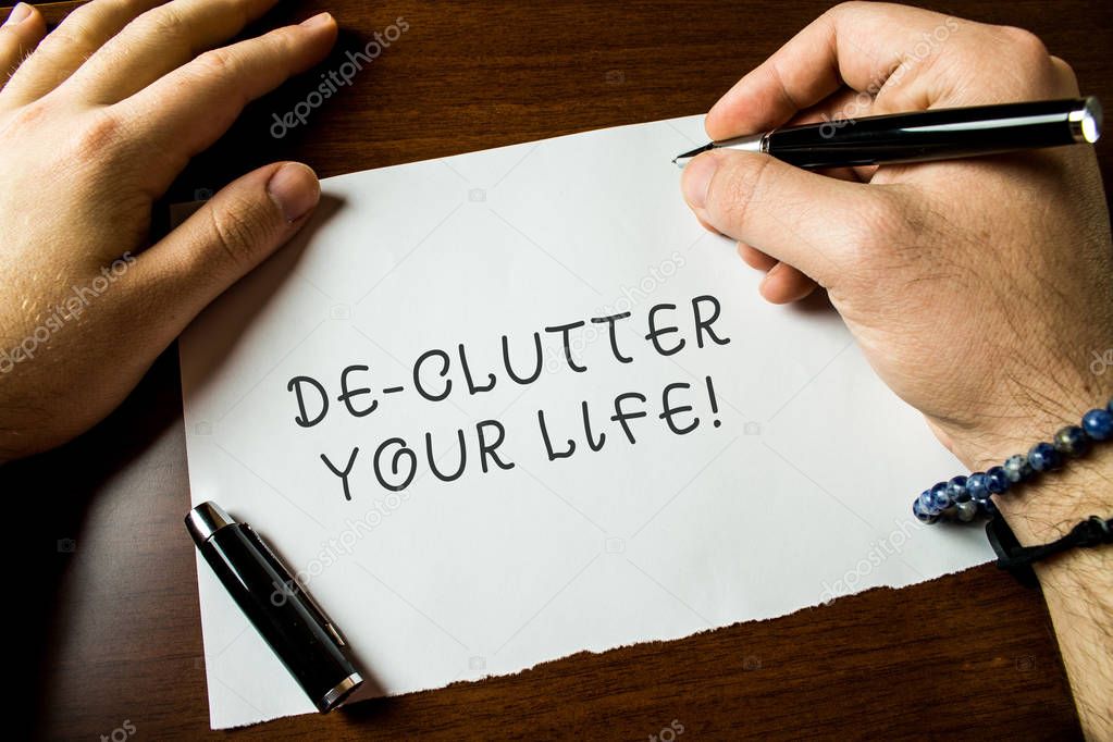 Text sign showing De Clutter Your Life. Conceptual photo remove unnecessary items from untidy or overcrowded places Close up view male hands writing blank stationary paper pens wooden table.